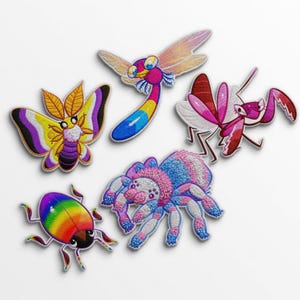 Puede incluir: Un conjunto de parches bordados de insectos, que incluyen una mariposa, una libélula, una mantis religiosa, un escarabajo y una araña. Los parches presentan colores vibrantes como el rosa, el azul, el amarillo y el morado, con costuras detalladas y diseños caprichosos.