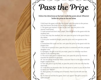 Puede incluir: Una tarjeta blanca con el texto "Pass the Prize" en una fuente decorativa. La tarjeta incluye instrucciones para un juego de despedida de soltera, con indicaciones para pasar un premio a los invitados. La tarjeta está sobre una superficie de madera.