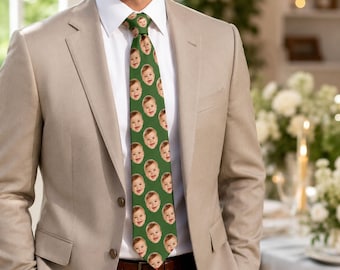 Puede incluir: Una corbata verde con un patrón de caras de bebé sonrientes. La corbata se lleva con una camisa blanca y una blazer beige. Un accesorio único y personalizado.