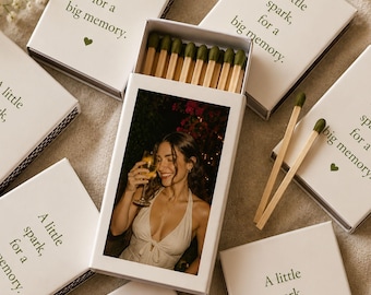 Puede incluir: Cajas de cerillas blancas con el texto "A little spark, for a big memory" y un corazón verde. Una caja está abierta, revelando cerillas y una foto de una mujer sosteniendo una bebida. Las cerillas tienen puntas verdes.