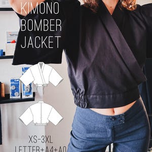 Op de afbeelding: Een zwart kimono-bomberjack met wijde mouwen en een geplooide elastische zoom. De afbeelding bevat de tekst KIMONO BOMBER JACKET en XS-3XL LETTER+A4+A0, samen met twee witte lijntekeningen die de voor- en achterkant van het kledingstuk tonen.