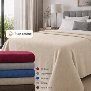 Può includere: Un copriletto a tinta unita con trama testurizzata, mostrato in tonalità sabbia su un letto. Una pila di copriletti piegati è presentata in sei colori: bordeaux, grigio medio, blu royal, tortora, testa di moro e sabbia, con il testo Puro cotone.