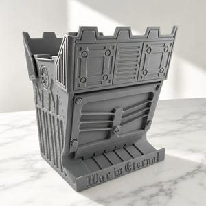 May include: A grey 3D printed dice tower featuring a fortress-like design with crenellated battlements, geometric panelling, and a small skull emblem. The base includes a tray with the embossed text War is Eternal in a gothic-style font.