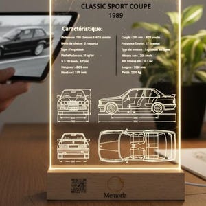 Puede incluir: Una pantalla acrílica iluminada que presenta un cupé deportivo clásico de 1989. La pantalla incluye especificaciones técnicas y esquemas del coche, sobre una base de madera. El texto "Classic Sport Coupe 1989" es visible.