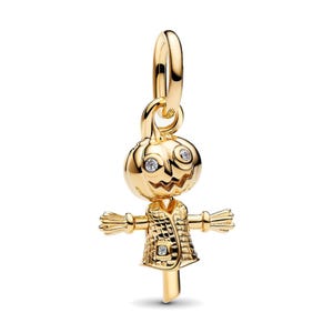 Può includere: Un charm color oro a forma di spaventapasseri con testa di zucca caratterizzata da due pietre chiare come occhi. La figura indossa un cappotto testurizzato con un dettaglio in pietra chiara sul davanti e ha le braccia tese. Include un occhiello.