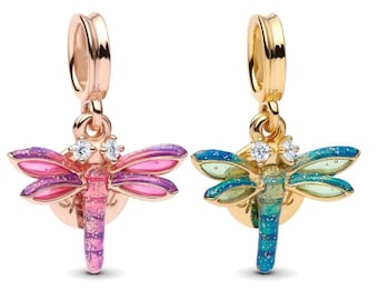 Peut inclure: Deux breloques libellules, une en or rose et une en or, chacune avec un motif de libellule décoratif. La breloque en or rose présente des ailes roses et violettes, tandis que la breloque en or a des ailes bleues et vertes. Les deux breloques ont une gemme transparente sur la tête.