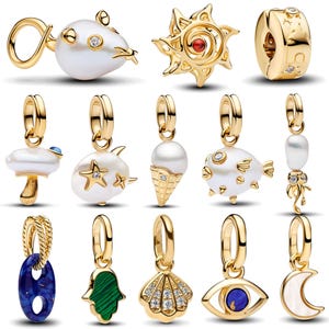 May include: A collection of gold-toned charms featuring various shapes including a white pearl mouse, a sun with a red center, a celestial bead, a mushroom, a starfish, an ice cream cone, a pufferfish, a jellyfish, a blue link, a hamsa, a shell, an eye, and a moon.