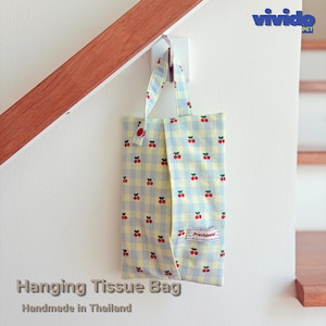 May include: A hanging tissue bag featuring a light blue and yellow gingham pattern with a small red cherry print. The fabric bag has a top handle and a rectangular white label with the text Providend stitched on the front lower right corner.