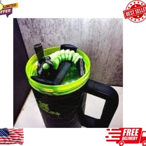 May include: A black and green insulated tumbler with a neon green rim and a black handle. The tumbler has a green and black design on the body and a black lid with a green accent. The tumbler has a straw and a green coiled design inside.