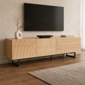 Könnte beinhalten: Ein helles Holz-Medienboard mit texturiertem Kreismuster auf den Schranktüren und Schubladen, getragen von einem schwarzen Metallrahmen. Eine weiße Keramikvase mit Zweigen und eine dunkle Schale stehen auf der flachen Oberfläche.