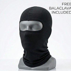May include: A black balaclava displayed on a mannequin head. The balaclava covers the entire head and neck, with an opening for the eyes. The text "FREE BALACLAVA INCLUDED" is visible in the upper right corner.