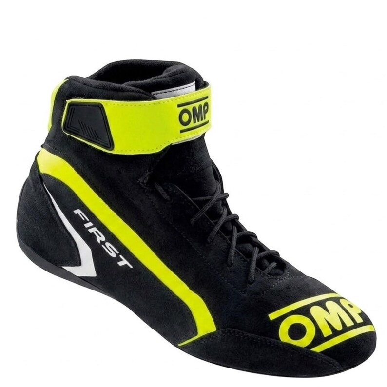 May include: A black high-top racing shoe featuring bright yellow accents, black laces, and a yellow ankle strap with the OMP logo. The word FIRST is printed in white on the side, and the OMP logo is printed in yellow on the toe area.