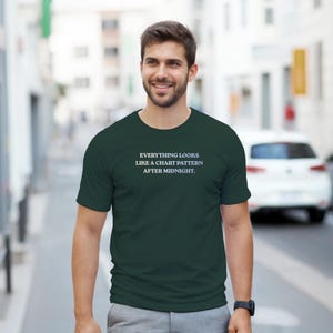 Könnte beinhalten: Ein dunkelgrünes T-Shirt mit dem weißen Text "EVERYTHING LOOKS LIKE A CHART PATTERN AFTER MIDNIGHT". Das Shirt hat kurze Ärmel und einen Rundhalsausschnitt. Die Person, die das Shirt trägt, lächelt.