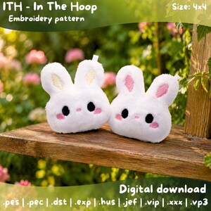 Könnte beinhalten: Zwei weiße Plüsch-Hasen-Spielzeuge mit rosa Akzenten, schwarzen Augen und rosigen Wangen, die auf einer Holzoberfläche präsentiert werden. Das Bild enthält den Text "ITH - In The Hoop Embroidery pattern" und "Digital download". Die Größe ist 4x4.