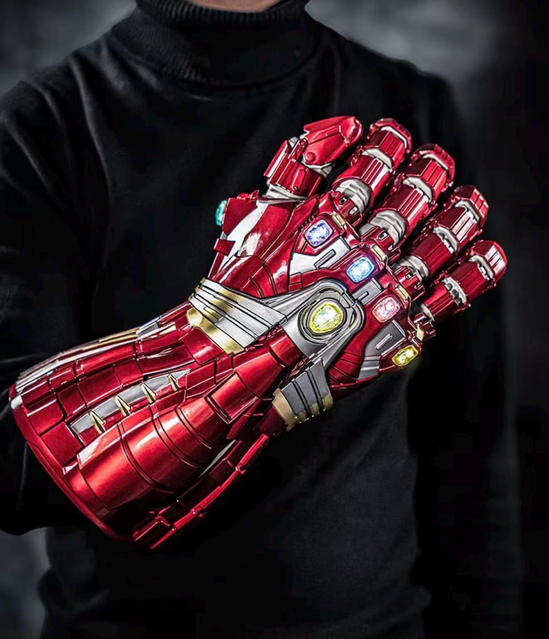 May include: A red and silver Iron Man gauntlet with multiple colored gems. The gauntlet is highly detailed with a metallic finish and is a replica of the one from the Avengers movies.