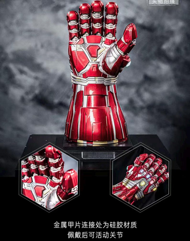May include: A red and silver metallic gauntlet with articulated fingers, displayed on a black base. The gauntlet features intricate paneling and detailing, with a glossy finish. The image includes close-up views of the gauntlet's design and text in Chinese.