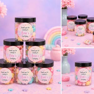 May include: Clear plastic jars filled with colorful star-shaped candies, each with a black lid and a label that reads "Thank you for coming to Evie's birthday". The jars are arranged on a pink surface with decorative elements.