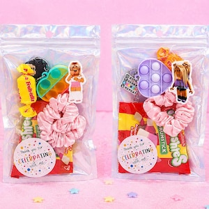 May include: Two clear resealable plastic bags filled with party favors, including a pink satin scrunchie, a small heart-shaped fidget toy, a character sticker, and candy. Each bag features a round sticker that reads Thank you for CELEBRATING with me.