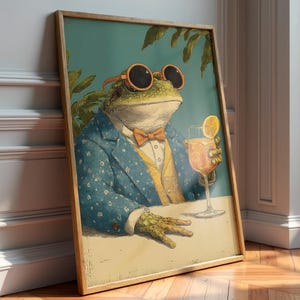Puede incluir: Impresión artística enmarcada que presenta una rana elegante con gafas de sol, un traje azul con lunares blancos y una pajarita naranja. La rana sostiene un cóctel con una rodaja de naranja. Estilo vintage.