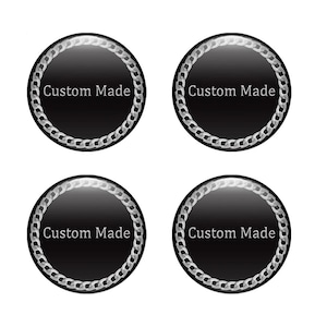 May include: Four black, circular buttons with a silver chain border and the text "Custom Made" in white. The buttons have a glossy finish and are arranged in a square formation against a white background.