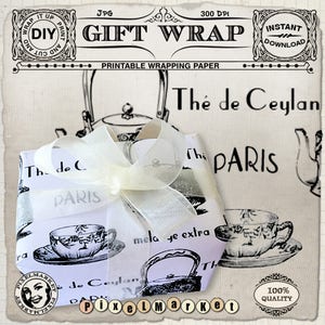 May include: A white gift box wrapped in a vintage-style tea themed paper with black and white illustrations of teapots and teacups. The paper has the text "The de Ceylan" and "Paris" printed on it. The box is tied with a white satin ribbon.