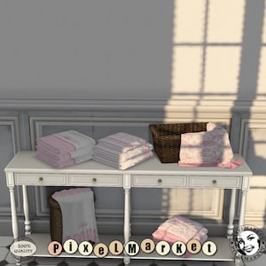May include: A white wooden table with three drawers and turned legs, displaying stacks of pink and white towels with floral embroidery. A wicker basket with a pink and white floral towel is also on the table.