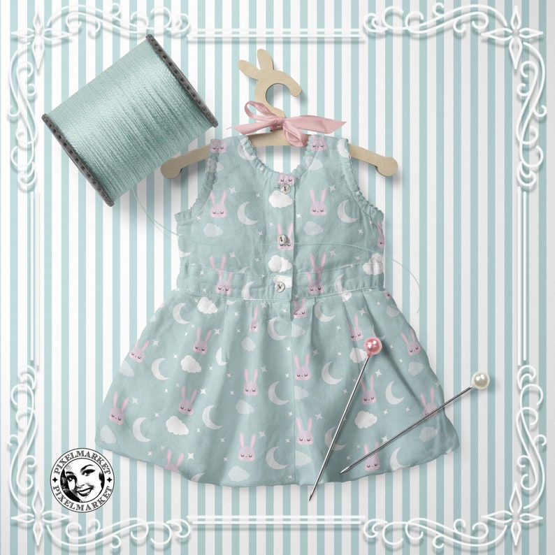 Peut inclure: Une robe sans manches bleu clair avec un motif de lapin blanc et rose. La robe a une fermeture boutonn&eacute;e blanche et est suspendue &agrave; un cintre en bois. La robe est sur un fond ray&eacute;.
