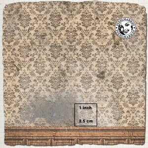 May include: A distressed, beige wallpaper with a brown damask pattern. The wallpaper has a large, light blue patch of missing paint. A wooden baseboard with a decorative moulding is at the bottom of the image. The text "1 inch" and "2.5 cm" is printed on a white rectangle.