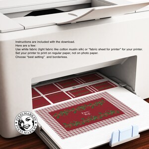 May include: A printer with a sheet of paper with a red and white plaid pattern and a Christmas-themed design with the text "Joyeux Noel" printed on it. The paper is being fed into the printer.