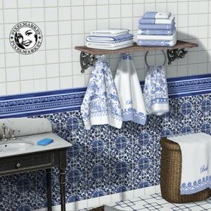 May include: A bathroom with blue and white patterned tile walls. A wooden shelf with a towel rack holds several white towels with blue floral designs. A blue and white patterned towel hangs on the rack. A blue and white patterned tile border runs along the top of the wall. A black and white vanity with a blue soap dish sits in the lower left corner of the image. A wicker basket with a white towel with blue trim sits in the lower right corner of the image.