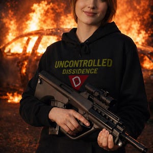 Puede incluir: Una persona con una sudadera negra con el texto "UNCONTROLLED DISSIDENCE" en amarillo y una "D" roja, sostiene un rifle negro. El fondo muestra una escena de fuego.