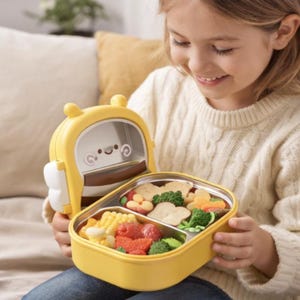 Pu&ograve; includere: Un portapranzo giallo e bianco con un design a forma di ape dei cartoni animati, aperto per rivelare un pasto di verdure e frutta. Il portapranzo ha un interno in acciaio inossidabile ed &egrave; diviso in scomparti. Il bambino che tiene il portapranzo indossa un maglione color crema.
