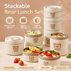 以下が含まれることがあります： クリームと茶色のスタッカブルベアランチセット。このセットには、クマのグラフィックで飾られたステンレス鋼のインテリアを備えた、いくつかの断熱容器が含まれています。容器には、野菜や果物など、さまざまな食品が詰められています。画像には「Stackable Bear Lunch Set」と書かれています。
