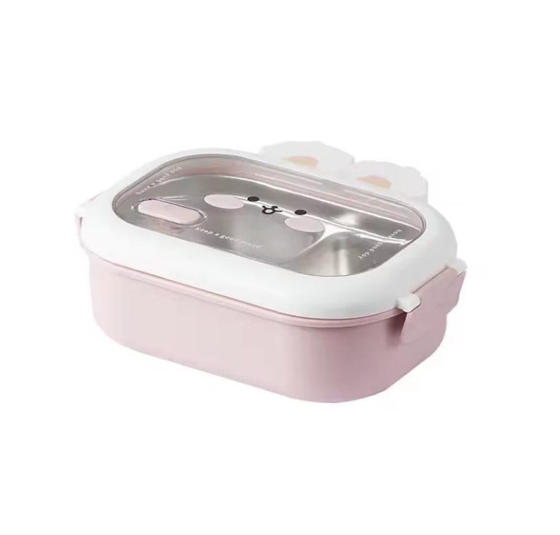 May include: A pink and white lunch box with a clear lid. The lid features a cartoon face and white bunny ears. The lunch box has a stainless steel interior and a pink base. The lid has a latch closure.
