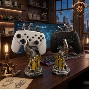 May include: Two robotic hand-shaped controller stands, one silver and gold with a white game controller and one silver and gold with a black game controller. Each stand features mechanical detailing, exposed springs, and a circular base for stability.