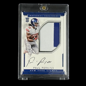 May include: A football trading card featuring Paul Perkins of the New York Giants. The card has a blue and white design with a patch and an autograph. The card is encased in a protective holder.