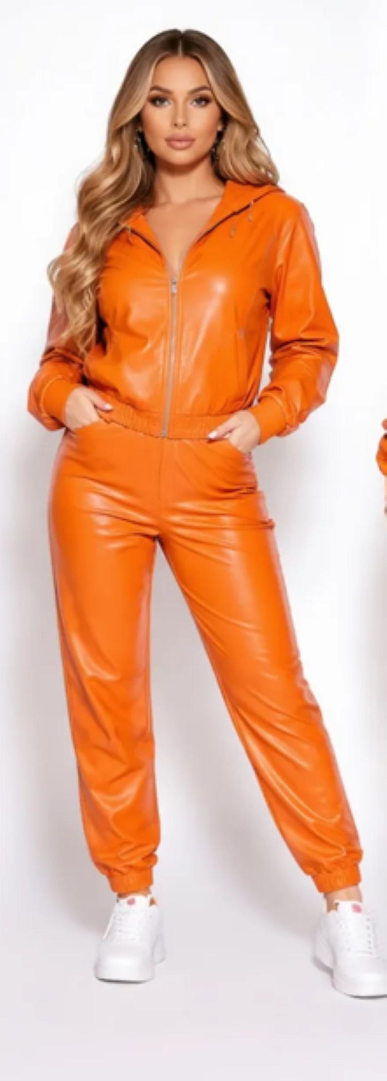May include: Orange faux leather tracksuit featuring a zip-up hooded jacket and matching pants. The jacket has pockets and the pants have an elastic waistband. White sneakers complete the outfit.