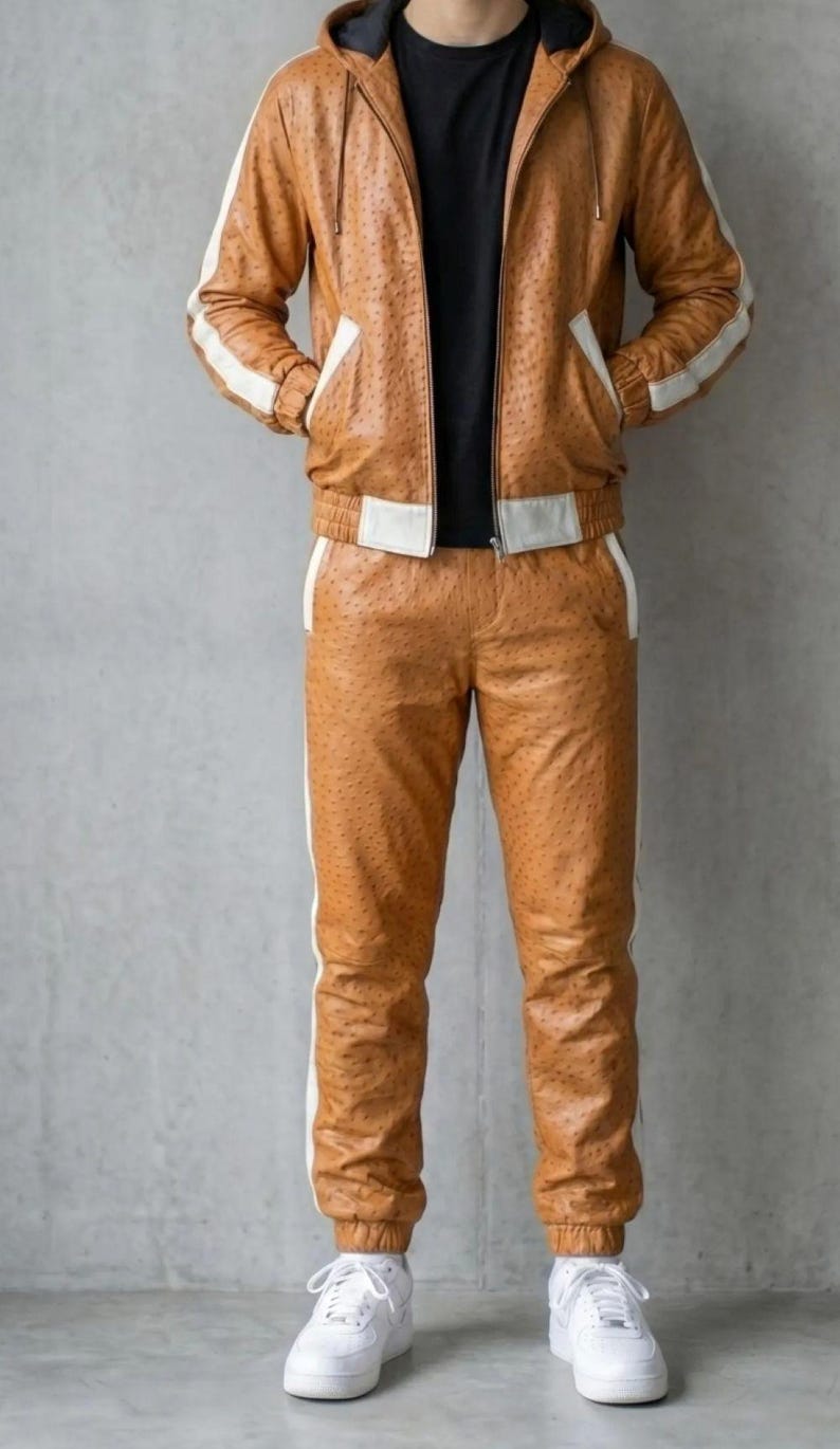 May include: A brown leather tracksuit with white stripes. The jacket has a hood and pockets, and the trousers have a matching stripe down the side. The outfit is paired with white trainers.