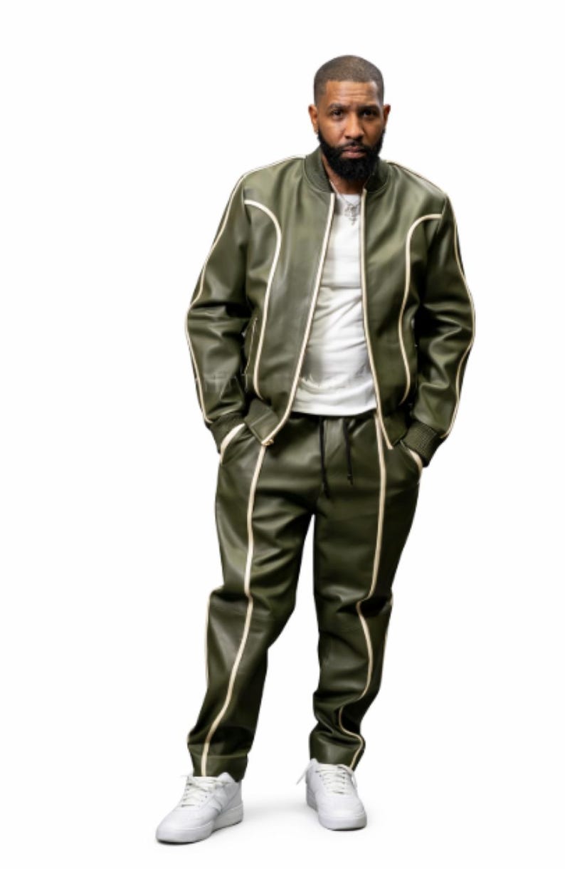 May include: Olive green track suit with cream-colored trim. The jacket has a zip-up front and the pants have a drawstring waist. The outfit is paired with white sneakers. The model is wearing a white t-shirt underneath the jacket.