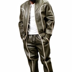 May include: Olive green leather tracksuit with white piping. The jacket is a bomber style with a zipper closure. The pants have a drawstring waist. The outfit is paired with white sneakers. The model is wearing a white t-shirt underneath.