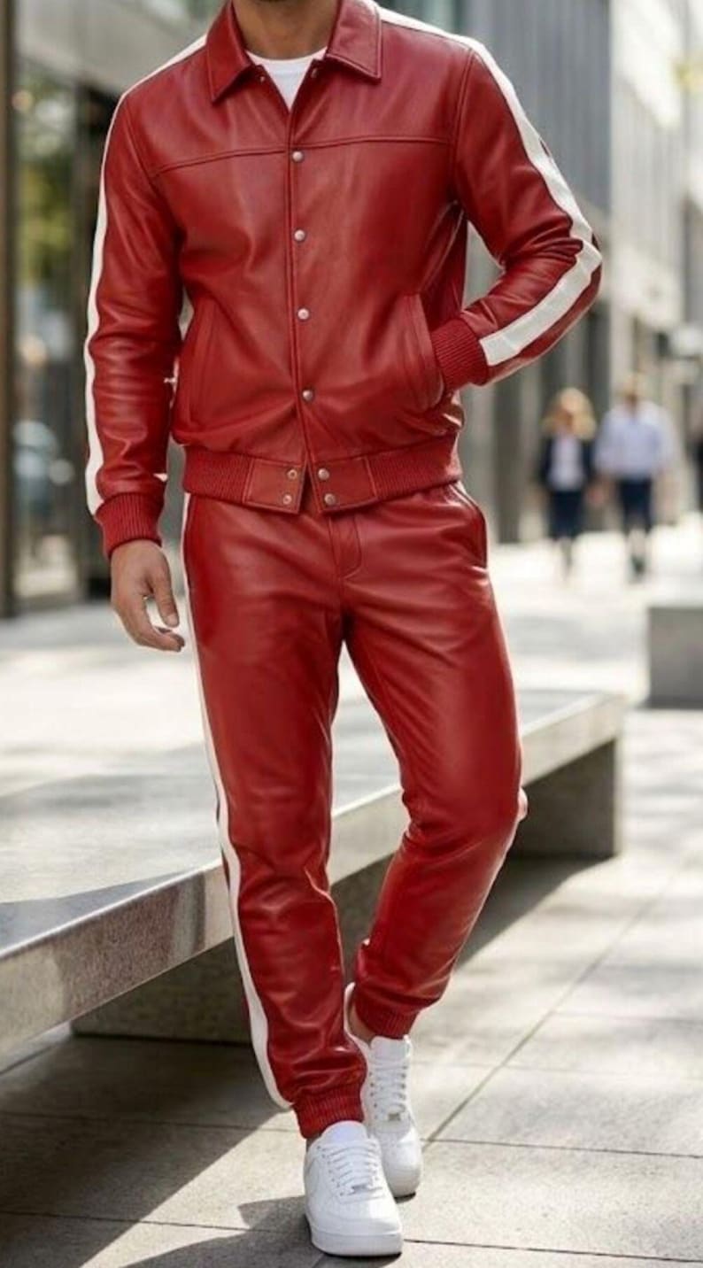 May include: A red leather jacket and trousers set with white stripes. The jacket features a button closure and pockets. The trousers have an elasticated waist and cuffs. The outfit is completed with white trainers.