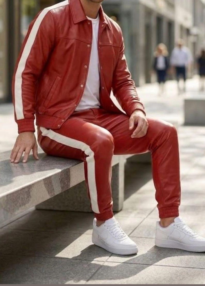May include: A red leather jacket and trousers set with white side stripes. The jacket features a button closure, and the trousers have a drawstring. White trainers complete the look. The outfit is a striking fashion choice.