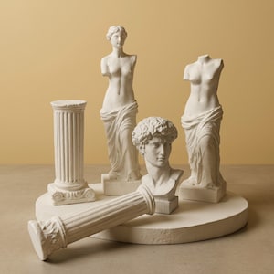 May include: A collection of white plaster sculptures, including two partial female figures, a bust of a man, and a column. The sculptures are arranged on a round, off-white platform, with a fallen column in the foreground. The background is a solid, muted yellow.