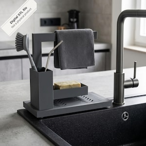 May include: A dark gray kitchen sink organizer featuring a rectangular base, a vertical brush holder, a horizontal bar for a cloth, and a small tray for a bar of soap. The text Digital STL file Not a physical product is visible in the corner.