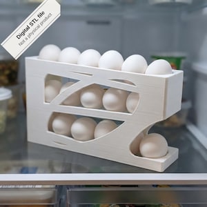 May include: A white 3D-printed egg dispenser rack with a slanted gravity-fed design holding twelve white eggs. A diagonal banner in the top left corner contains the text Digital STL file Not a physical product in black lettering.