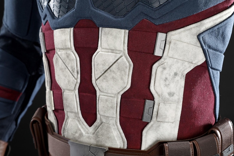 May include: Close-up of a Captain America costume chest piece. The design features a red and white colour scheme with a textured, weathered appearance. The chest piece is part of a larger costume.