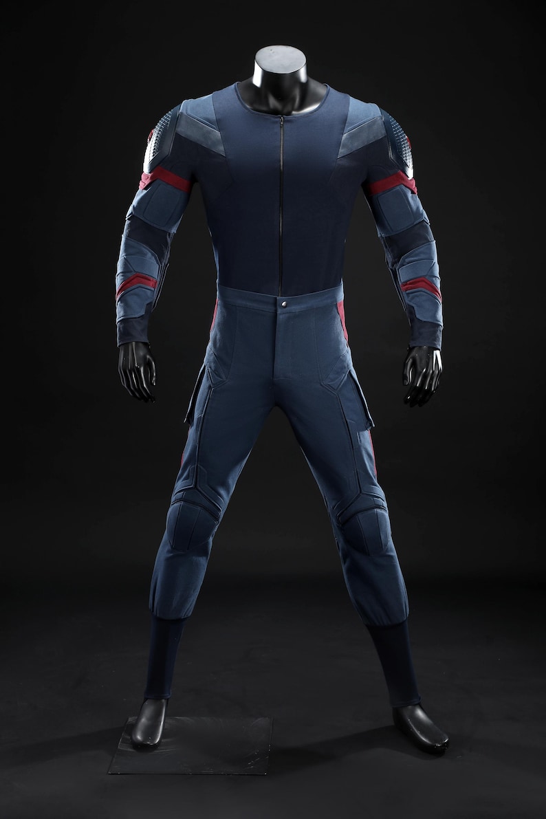 May include: A navy blue jumpsuit with red and grey accents, displayed on a mannequin. The suit features a zip-up front, padded shoulders, and cargo pockets. The sleeves and legs have red stripes and grey panels.