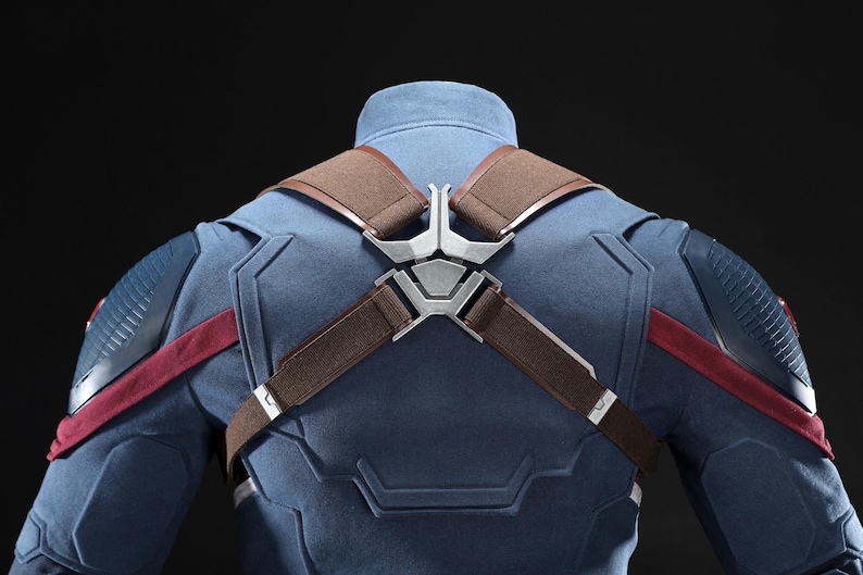 May include: A blue and red costume with brown straps and silver metal accents. The costume has a high collar and detailed shoulder and chest design. The back of the costume is visible against a dark background.