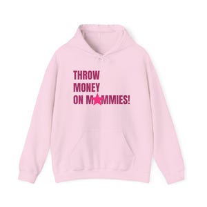 May include: A light pink hoodie with a front pocket and drawstring hood. The text "THROW MONEY ON MAMMIES!" is printed in a darker pink color, with a star graphic replacing the letter "A" in "MAMMIES!"