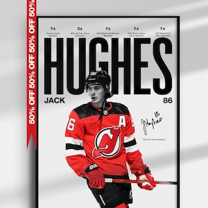 Peut inclure: Une affiche de sport encadrée montrant Jack Hughes dans un maillot de hockey rouge des New Jersey Devils. Le texte indique HUGHES, JACK, 86, et comprend une liste de réalisations, une signature et la citation, "You're in the moment."